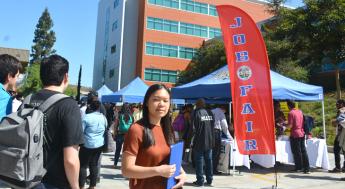 student standing near job fair banner and job fair event