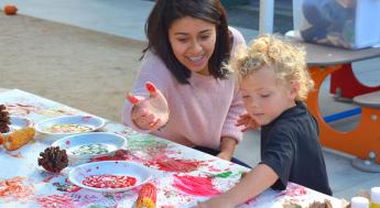 pre-school staffer helping child paint