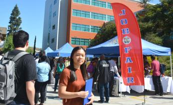 student standing near job fair banner and job fair event