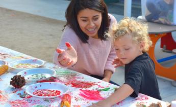 pre-school staffer helping child paint