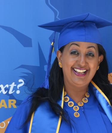 Mother in graduation robe posing with teen daughter