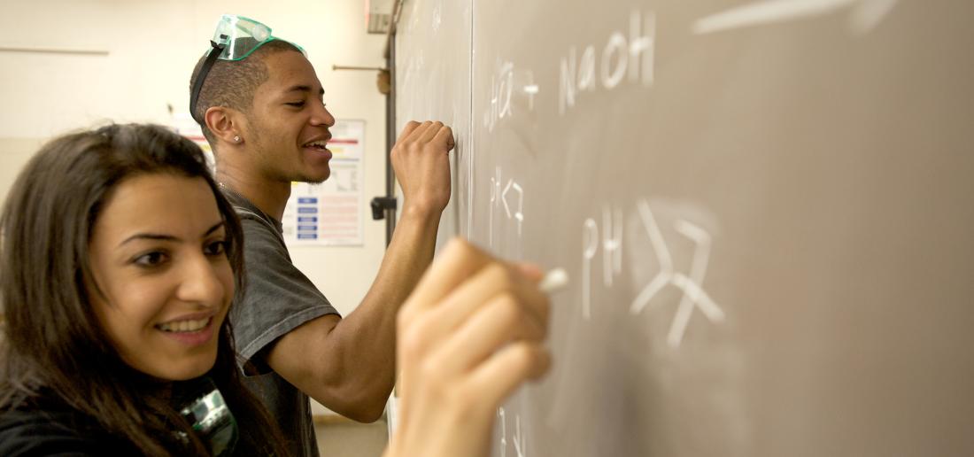 Two Students Writing on Blackboard